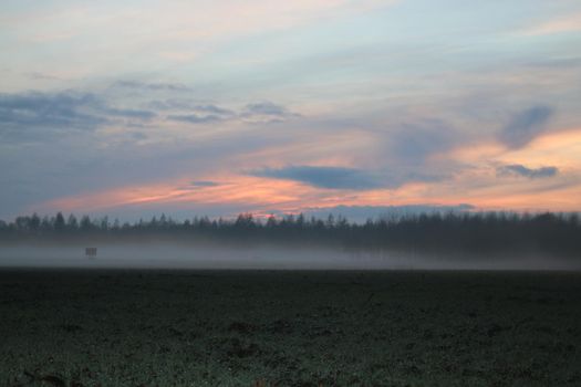 A landscape in the evening with fog and sunset
