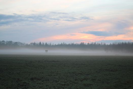 A landscape in the evening with fog and sunset