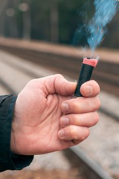 The Firecracker in a Hand. Man Holding a Burning Petard in His Hand. A Human with a Pyrotechnics that Burns with Sparks and Smoke Outdoors