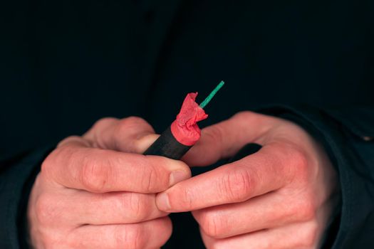 The Firecracker in a Hand. Man Holding a Black Petard in His Hand. A Human with a Pyrotechnics Outdoors