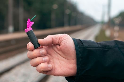 The Firecracker in a Hand. Man Holding a Black Petard in His Hand. A Human with a Pyrotechnics Outdoors