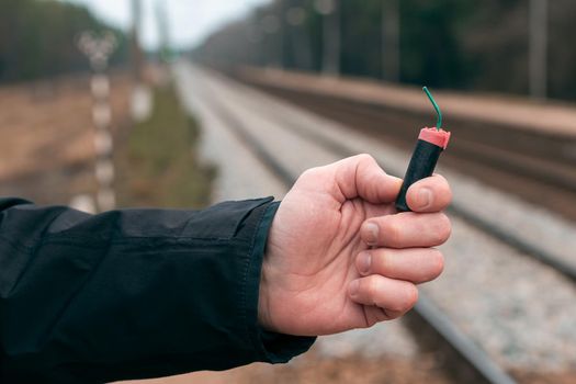 The Firecracker in a Hand. Man Holding a Black Petard in His Hand. A Human with a Pyrotechnics Outdoors