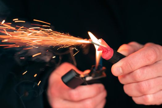 The Firecracker in a Hand. Man Holding a Burning Petard in His Hand. A Human with a Pyrotechnics that Burns with Sparks and Smoke Outdoors