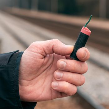 The Firecracker in a Hand. Man Holding a Black Petard in His Hand. A Human with a Pyrotechnics Outdoors