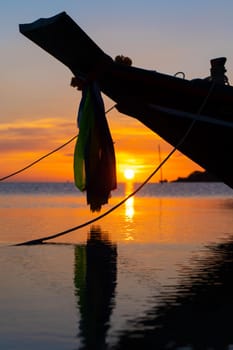 Beautiful sunset on the coast of a tropical island in Thailand, a silhouette of a boat in the ocean.