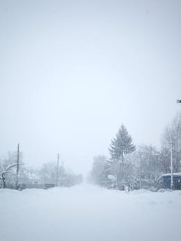Winter landscape. A distant village in the cold part of the planet. White snow covered road.