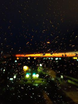 Raindrops on glass. Livin during sunset. Night sky with a bright orange stripe.