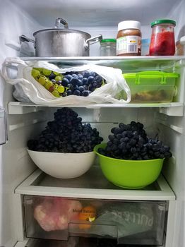 Open refrigerator shelves are stocked with groceries and fruits.