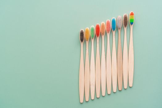 A set of Eco-friendly antibacterial toothbrushes made of bamboo wood on a light green background. Environmental care trends.