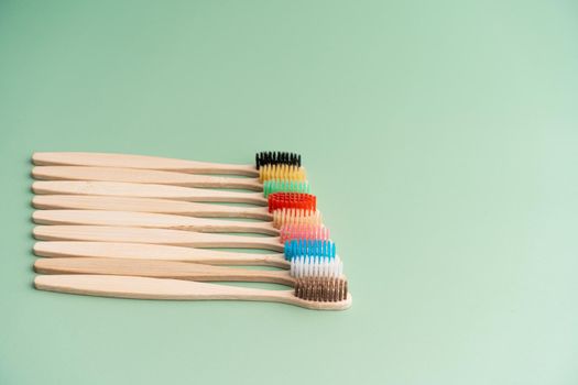 A set of Eco-friendly antibacterial toothbrushes made of bamboo wood on a light green background. Environmental care trends.