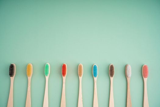 A set of Eco-friendly antibacterial toothbrushes made of bamboo wood on a light green background. Environmental care trends.