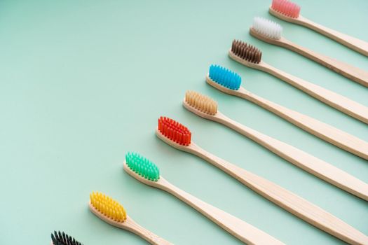 A set of Eco-friendly antibacterial toothbrushes made of bamboo wood on a light green background. Environmental care trends.