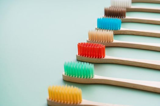 A set of Eco-friendly antibacterial toothbrushes made of bamboo wood on a light green background. Environmental care trends.