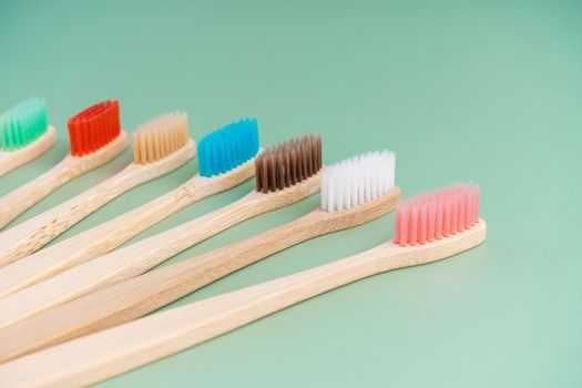 A set of Eco-friendly antibacterial toothbrushes made of bamboo wood on a light green background. Environmental care trends.