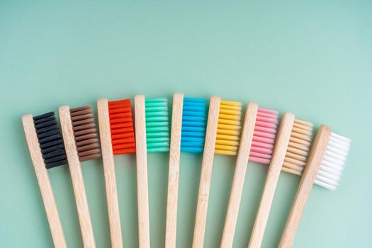 A set of Eco-friendly antibacterial toothbrushes made of bamboo wood on a light green background. Environmental care trends.