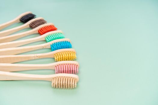 A set of Eco-friendly antibacterial toothbrushes made of bamboo wood on a light green background. Environmental care trends.