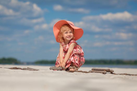 A little girl in a beautiful sarafna plays in the sand on the beach.