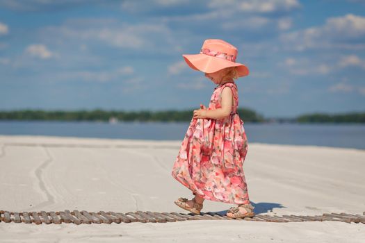 A little girl in a beautiful sarafna plays in the sand on the beach.