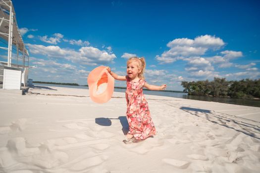 A little girl in a beautiful sarafna plays in the sand on the beach.