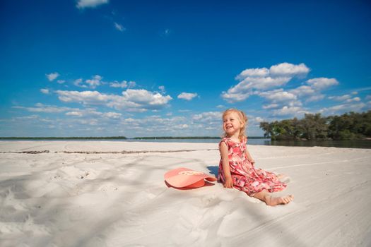 A little girl in a beautiful sarafna plays in the sand on the beach.