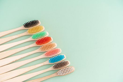 A set of Eco-friendly antibacterial toothbrushes made of bamboo wood on a light green background. Environmental care trends.