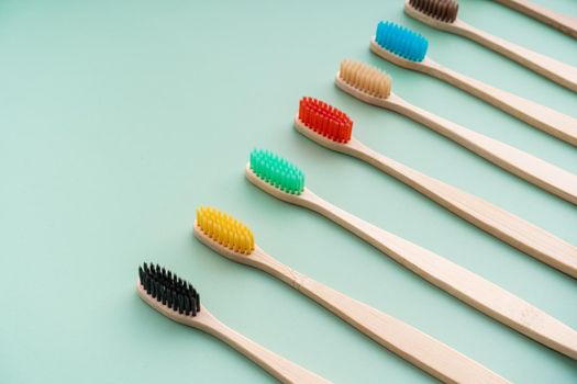 A set of Eco-friendly antibacterial toothbrushes made of bamboo wood on a light green background. Environmental care trends.