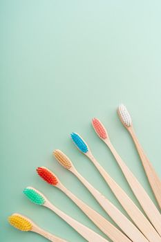 A set of Eco-friendly antibacterial toothbrushes made of bamboo wood on a light green background. Environmental care trends.