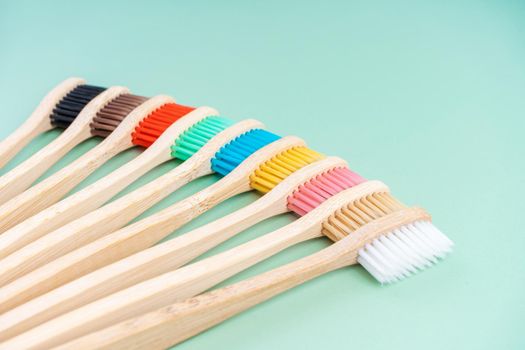 A set of Eco-friendly antibacterial toothbrushes made of bamboo wood on a light green background. Environmental care trends.