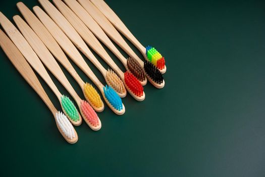 A set of Eco-friendly antibacterial toothbrushes made of bamboo wood on a dark green background. Environmental trends.