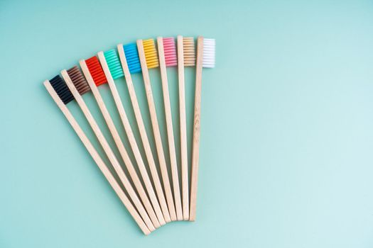 A set of Eco-friendly antibacterial toothbrushes made of bamboo wood on a light green background. Environmental care trends.