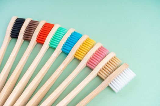 A set of Eco-friendly antibacterial toothbrushes made of bamboo wood on a light green background. Environmental care trends.