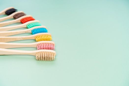 A set of Eco-friendly antibacterial toothbrushes made of bamboo wood on a light green background. Environmental care trends.