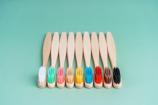 A set of Eco-friendly antibacterial toothbrushes made of bamboo wood on a light green background. Environmental care trends.