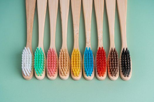 A set of Eco-friendly antibacterial toothbrushes made of bamboo wood on a light green background. Environmental care trends.