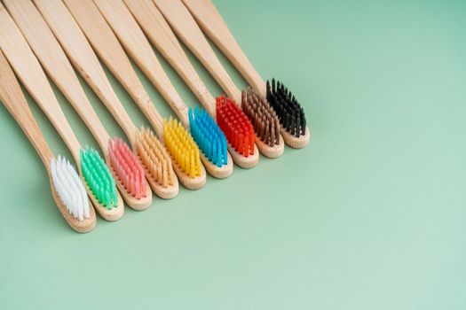 A set of Eco-friendly antibacterial toothbrushes made of bamboo wood on a light green background. Environmental care trends.