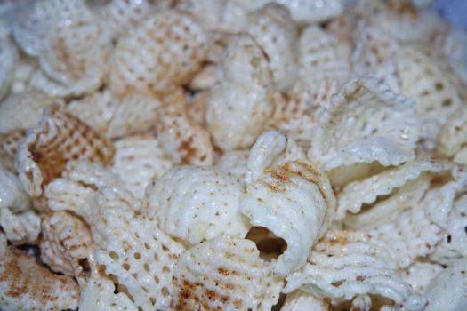 Closeup view of freshly fried chips as fast food for tea break. Potato chips with spices sprinkled on it. Fast food background for advertisements.