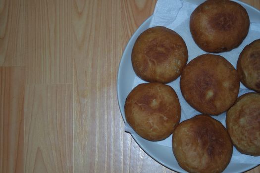 Closeup view of homemade tasty potato bread rolls bun placed in a white plate over a wooden floor.