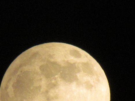 Earth's Moon Glowing On Black Background. The Moon close-up on a black night sky shot through a telephoto camera.