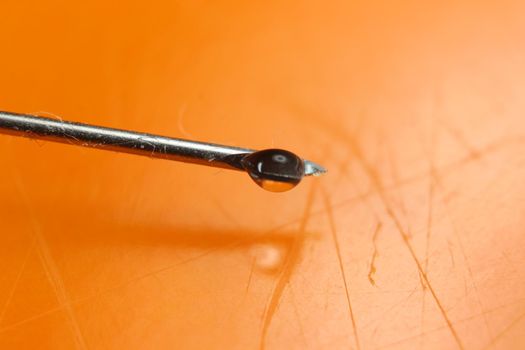 Close-up of vaccine drop on syringe needle. Water drop falling from the syringe needle