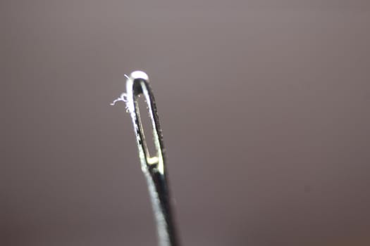 Macro photograph of sewing needle. Small needle with empty eyelet, isolated over the black background.