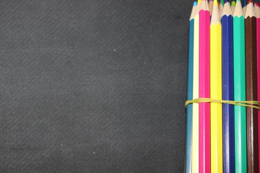 Close-up view of bright colored multicolor pencils on black background