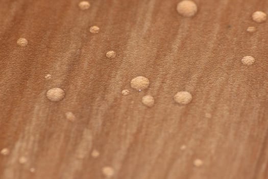 Closeup selective focus view of water drops on wooden floor. Abstract raindrops pattern on wooden board