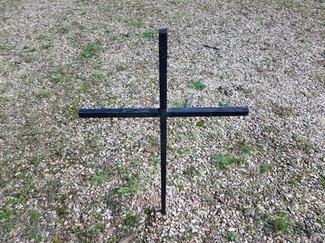 black cross in lawn or yard with stones or pebbles