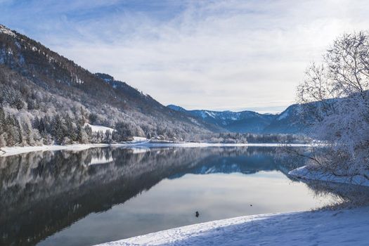 Idyllic winter landscape: Reflection lake, snowy trees and mountains