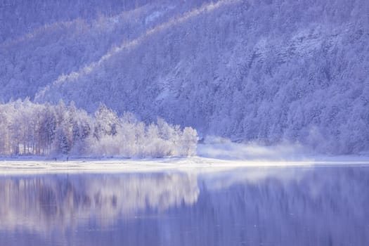 Idyllic winter landscape: Reflection lake, snowy trees and mountains