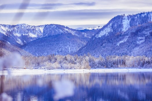 Idyllic winter landscape: Reflection lake, snowy trees and mountains