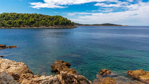 Croatia. South Dalmatia. Rocky shore. An island overgrown with trees is visible in the distance