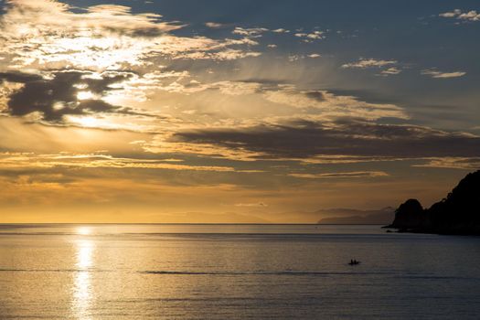 Silhouette of a kayak at sunrise in Abel Tasman National Park, New Zealand.