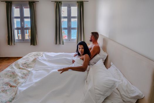 couple in white bed looking out over ocean during luxury vacation in Greece. High quality photo