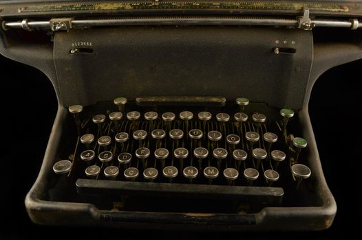 A closeup view of a vintage typewriter over a black background.